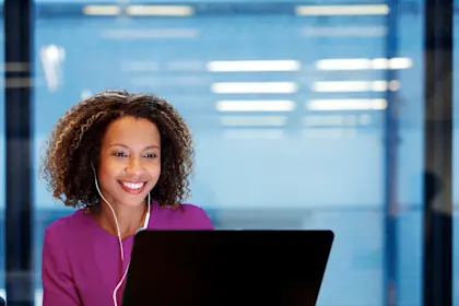 Woman wearing headphones smiling at her laptop