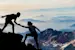 Hikers helping each other climb a mountain