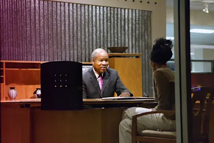 Man sits behind desk and interviews woman