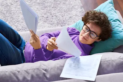 woman lying on sofa and analyzing papers