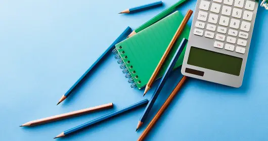 Pencils, calculator and notebook on table