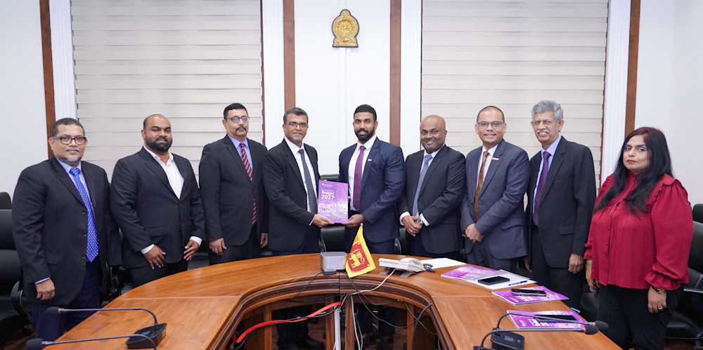 Group of AICPA CIMA representatives standing around a conference table during the presentation of AICPA & CIMA’s Sri Lanka National Budget Proposal Submission 2027, with a copy of the proposal being handed over in a meeting room.