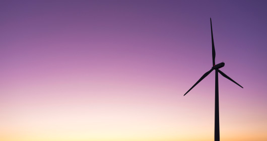Wind turbine in a meadow at sunset