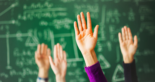 Student's raised hands in front of chalk board