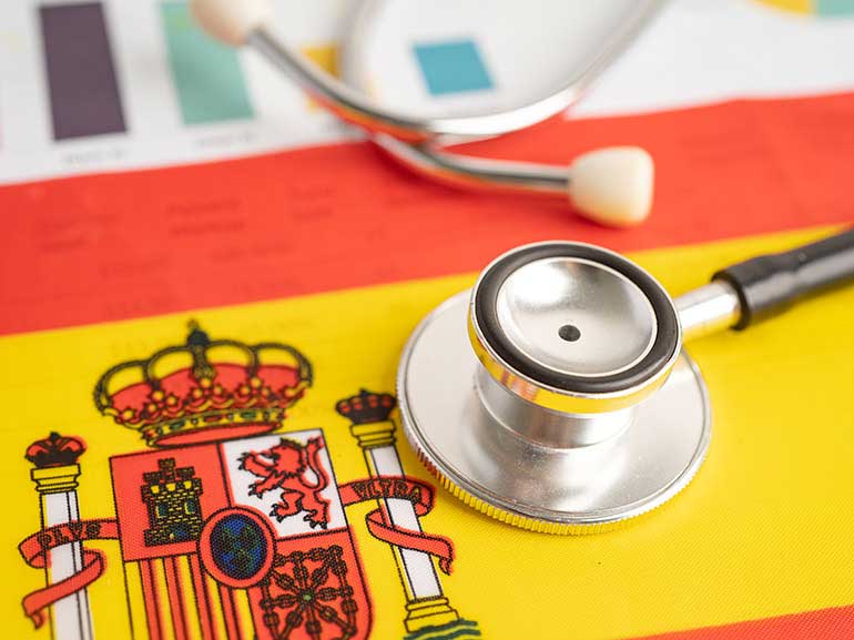 Estetoscopio negro sobre la bandera española: concepto de salud de mercado