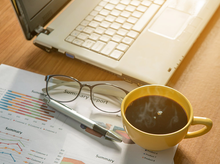 Trading desk setup: laptop, chart, and coffee