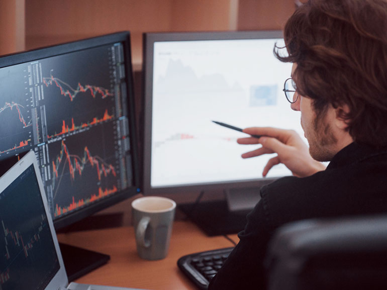 Trader che analizza i mercati lavorando alla scrivania