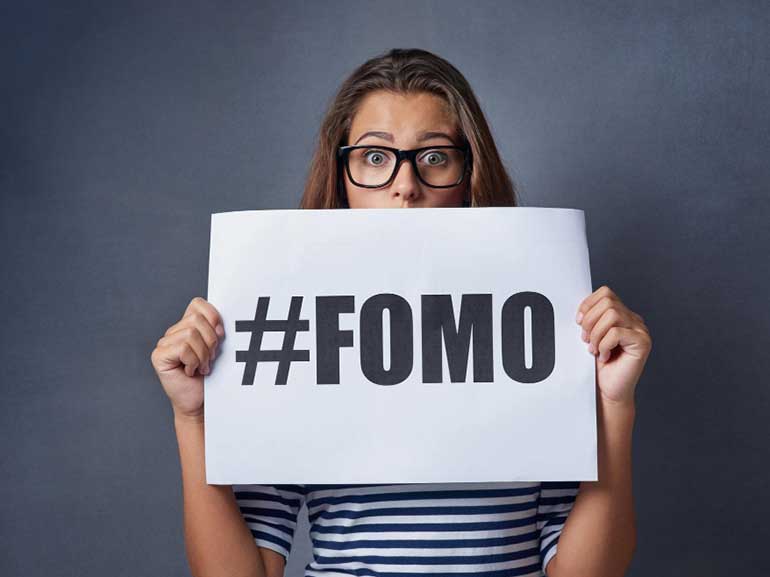 امرأة تحمل لافتة عليها هاشتاغ FOMO