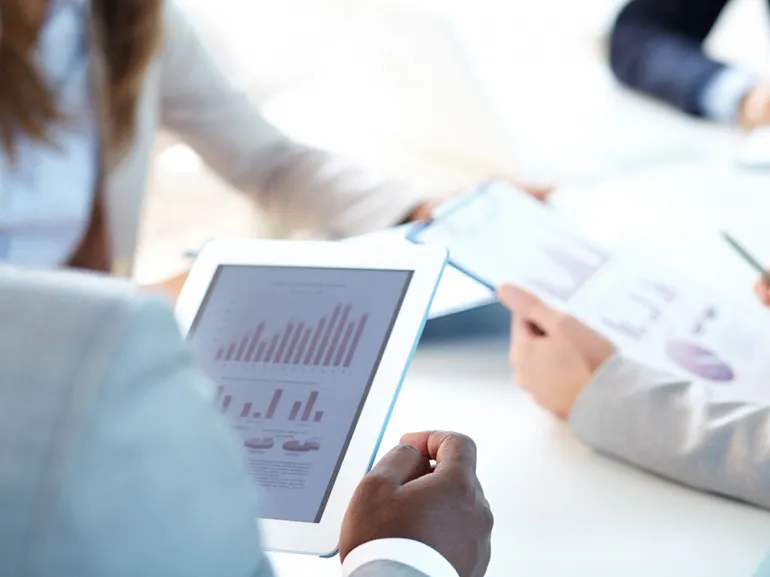 Ejecutivo sosteniendo una tableta digital con diagramas.