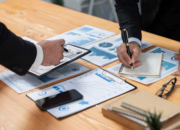 Two men in suits are signing a document with a graph on it