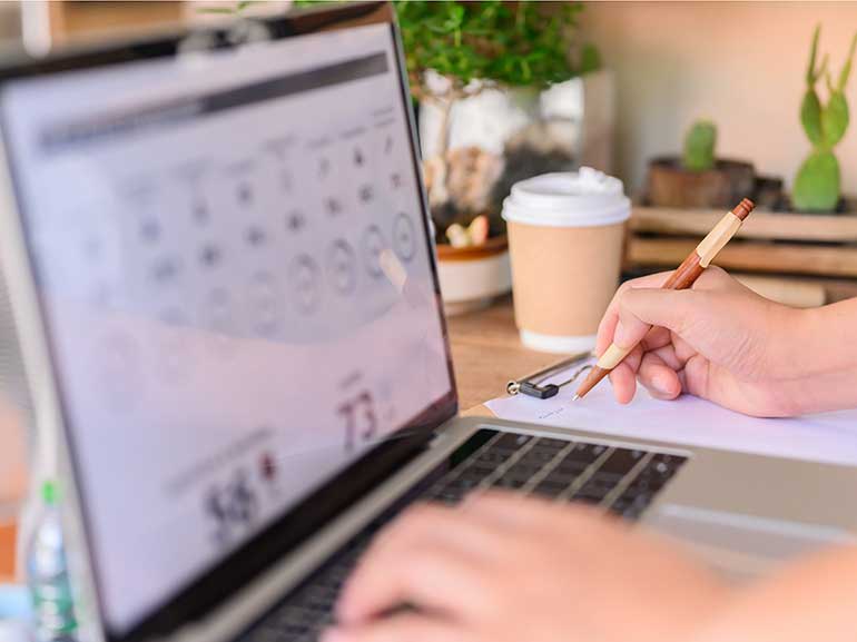 Eine Frau arbeitet an einem Laptop und macht sich Notizen