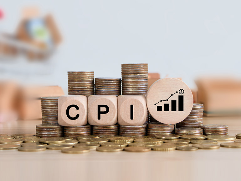Bloques de madera del IPC encima de pilas de monedas