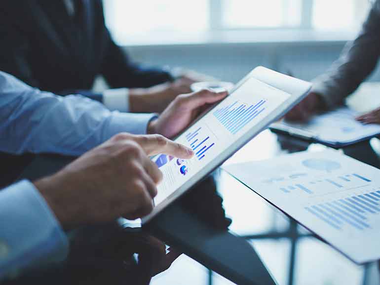 Businessmen reviewing financial data via digital charts and graphs on a tablet