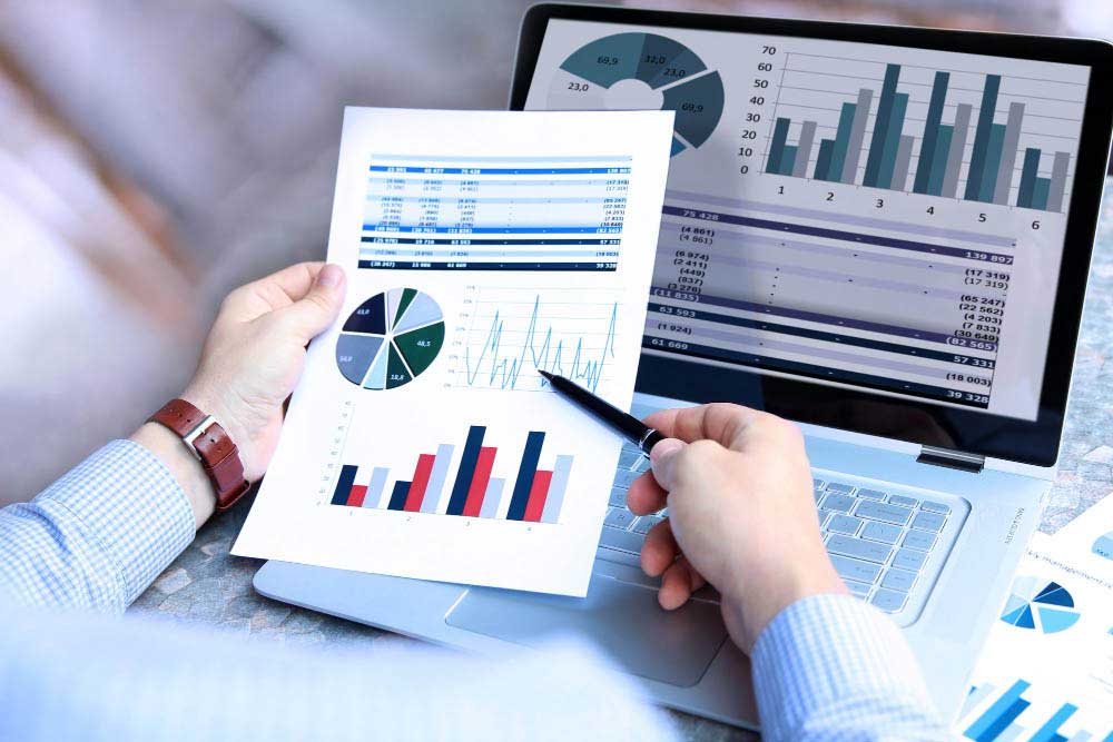 Empresarios comparando gráficos en papel con datos en la pantalla de un portátil