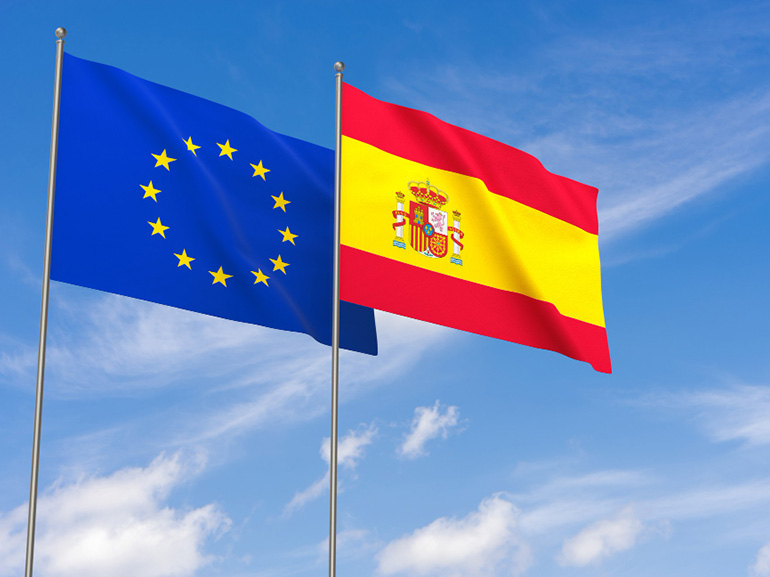 European union and spain flags over blue sky background