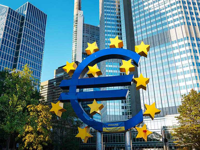 Znak euro z gwiazdami na tle biurowców
