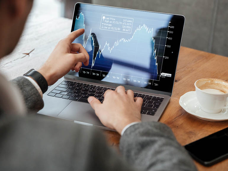 Empresario analizando gráficos financieros en la pantalla de un ordenador portátil.