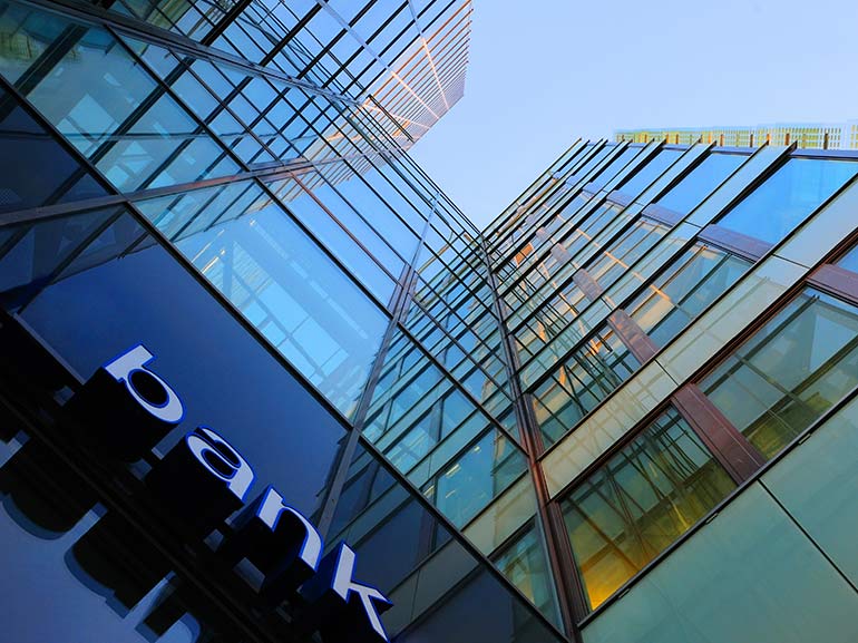 An image of big bank building and a sign on which the word bank is written