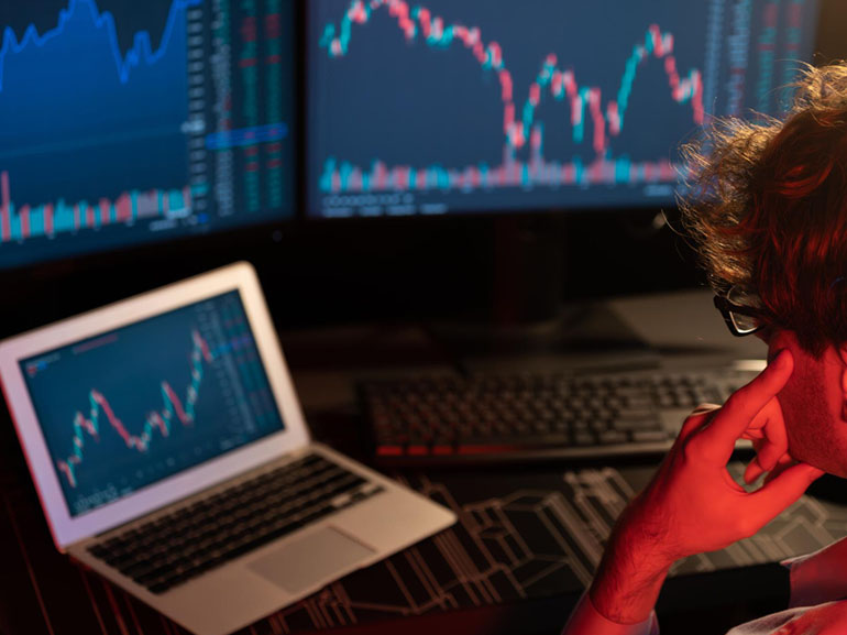 Trader che analizza i grafici del mercato azionario su più schermi