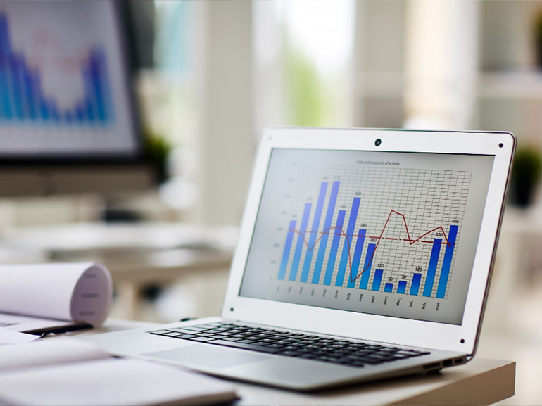 Laptop displaying a bar and line graph in an office setting