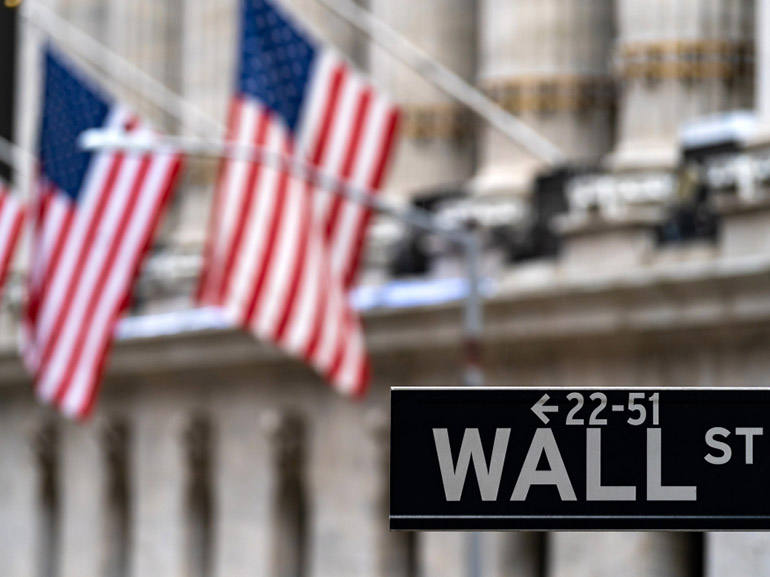 Das Wall-Street-Zeichen im Hintergrund des Börsengebäudes mit seinen US-Flaggen