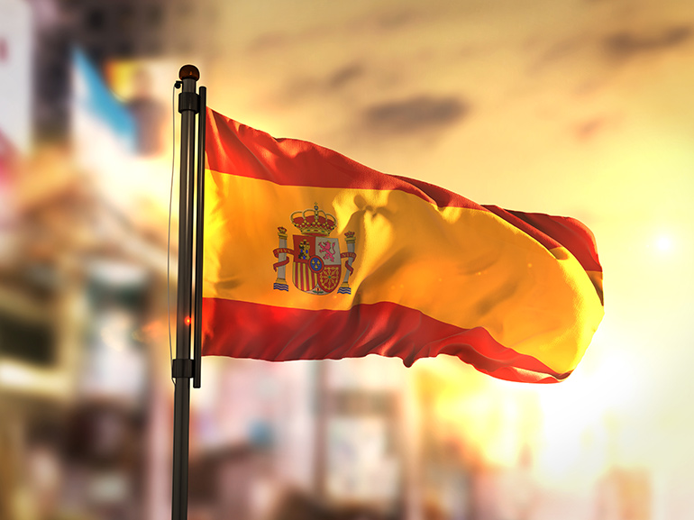 Bandera de España sobre fondo borroso al amanecer a contraluz