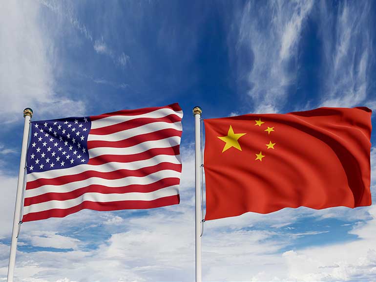 Banderas estadounidense y china sobre un cielo azul