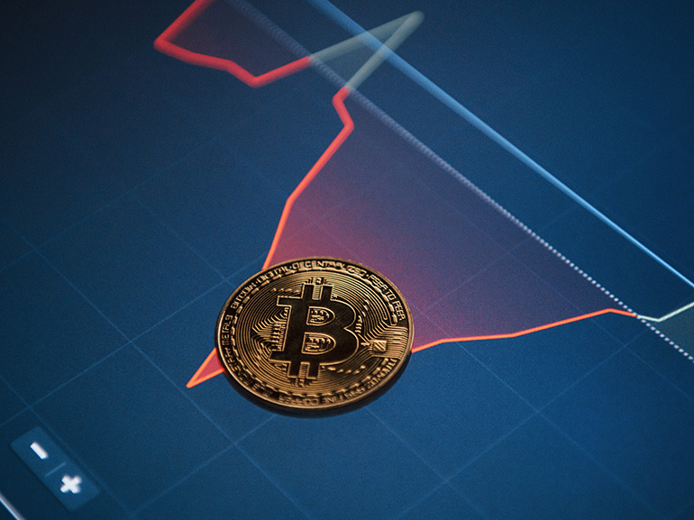 Golden bitcoin coin displayed on top of a financial chart