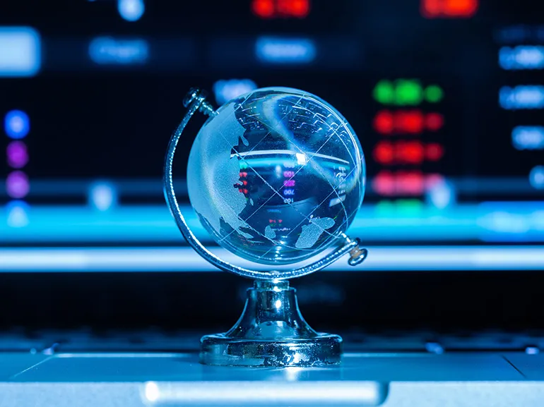 Globo di cristallo su uno sfondo di informazioni di borsa