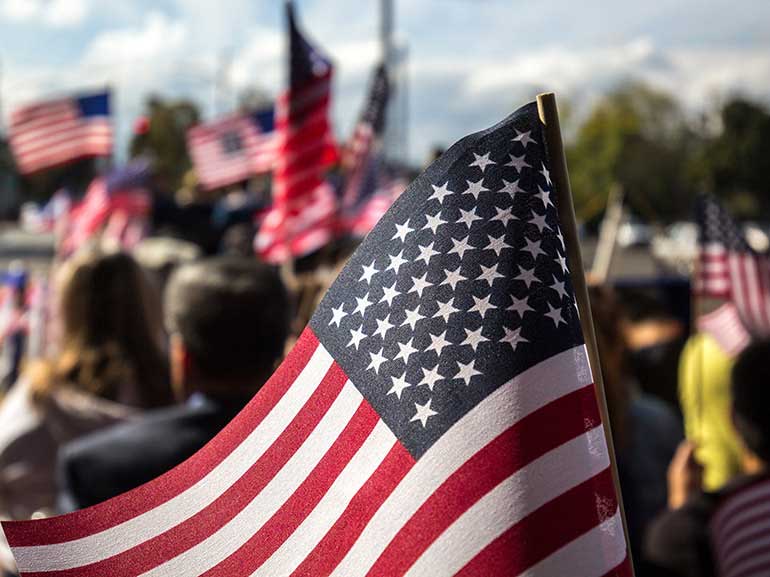 A waving US flag, part of a gathering of people with flags