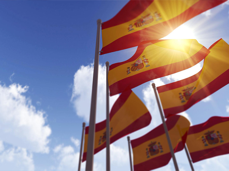 Spain flags waving in the wind against a blue sky