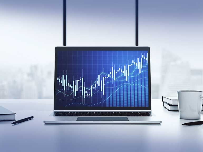 Laptop na biurku z otwartym na ekranie wykresem finansowym