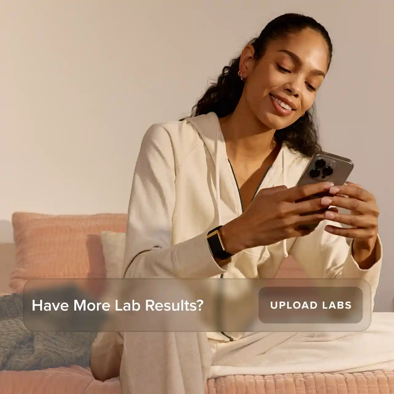 Woman wearing a WHOOP wearable while reviewing health data on her phone, illustrating lab result uploads and personalized health and performance insights.