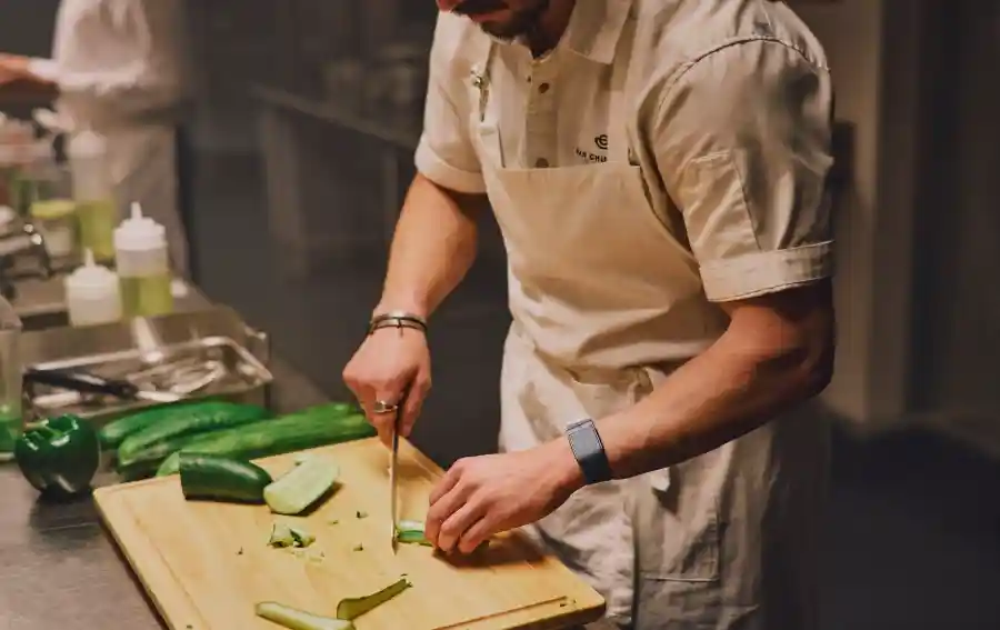 Chef wearing a WHOOP wearable while preparing food in a professional kitchen, highlighting all-day heart rate monitoring, strain tracking, and performance insights during daily activity.