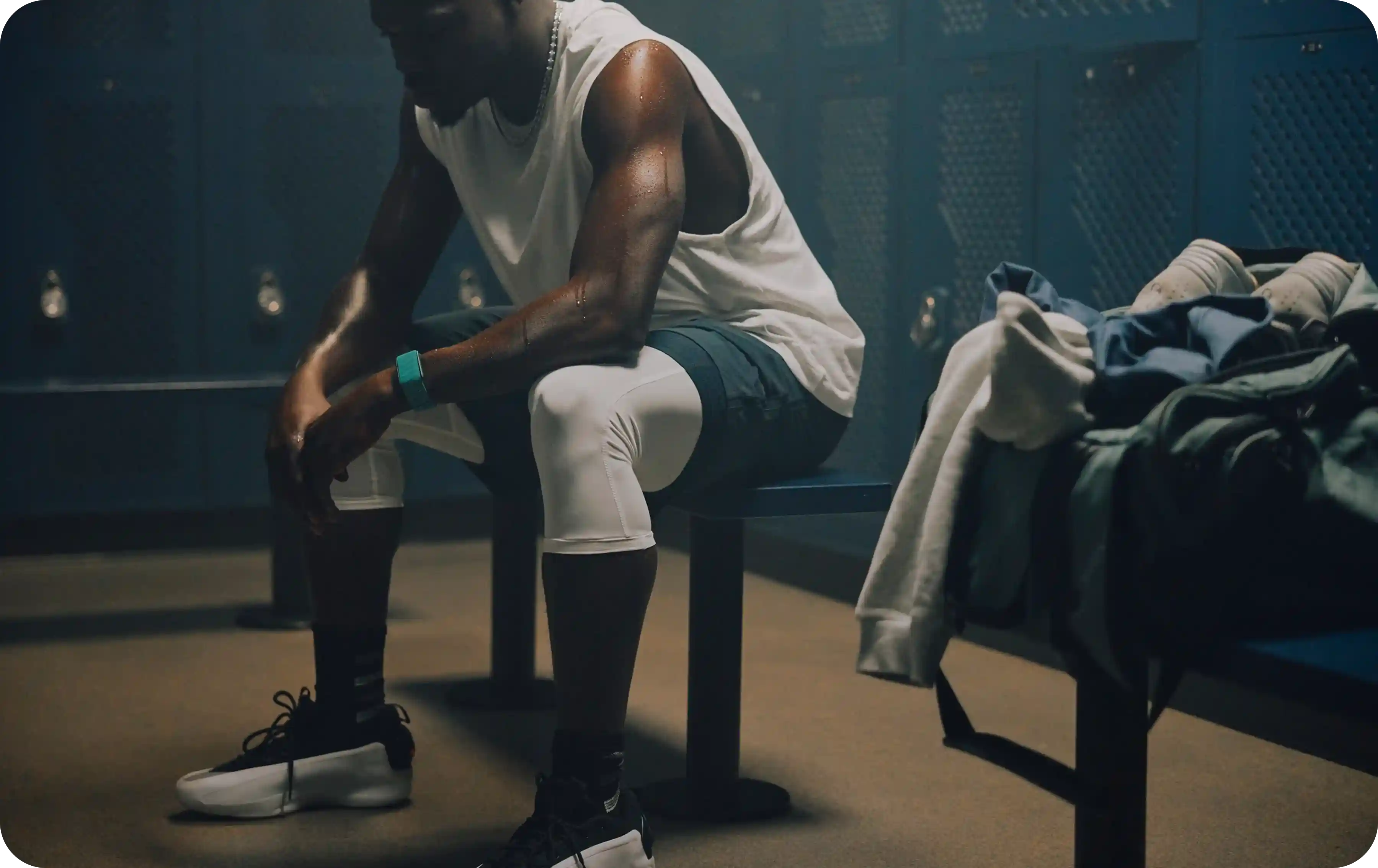 After an intense workout, an athlete sits on a locker room bench wearing a WHOOP 5.0 band, tracking heart rate, training strain, and recovery during the post-session cooldown.