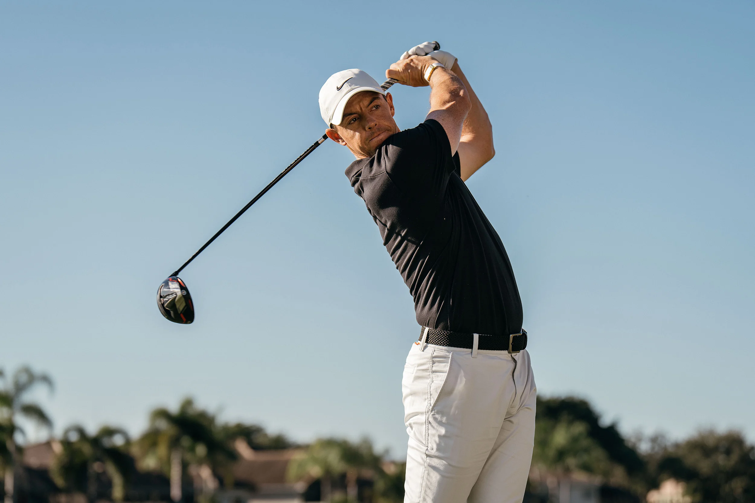 A man swings a golf club while sporting the Arctic-colored WHOOP 4.0 Band 