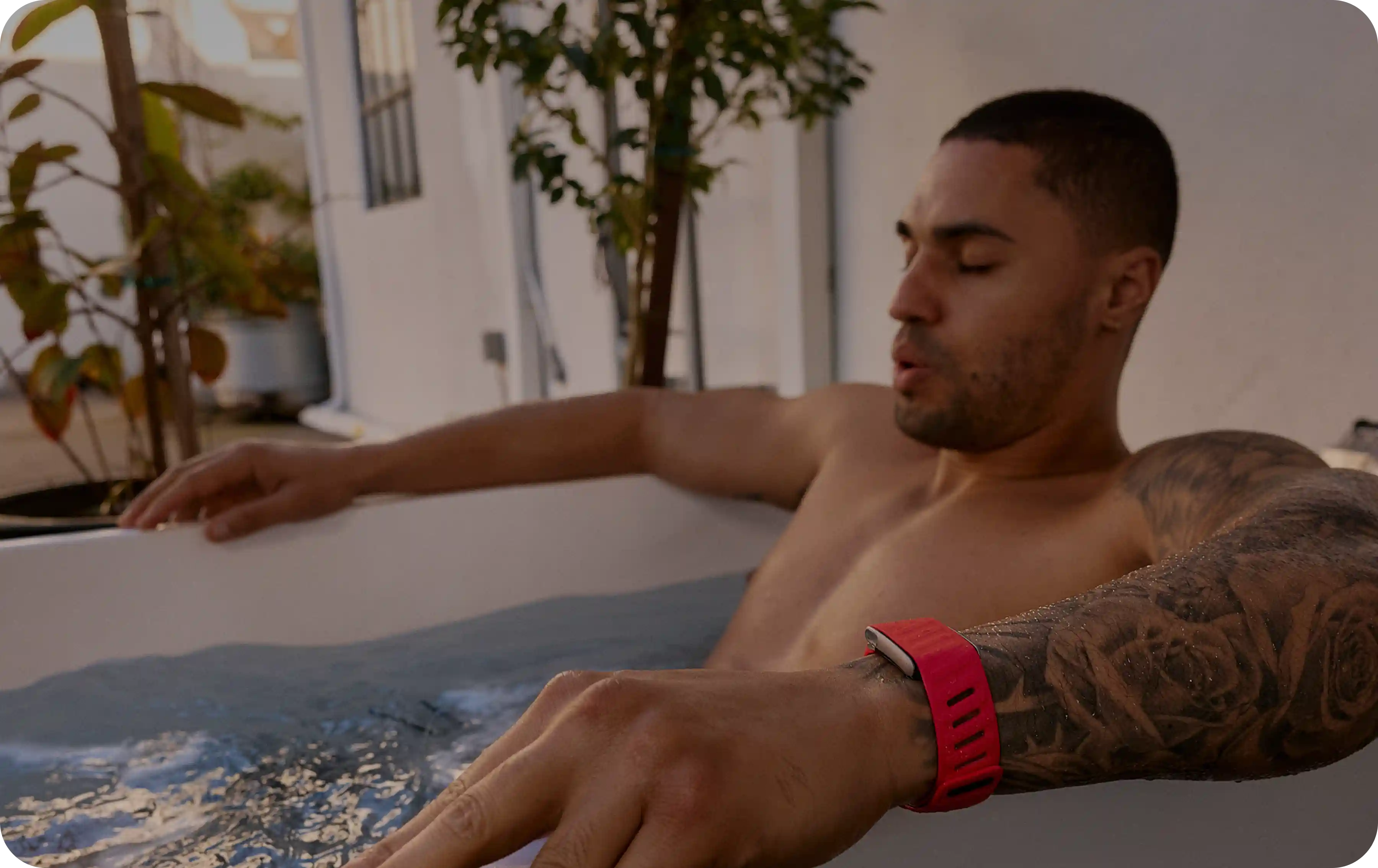 Person wearing a WHOOP 5.0 band while seated in an outdoor tub for a cold-plunge recovery soak, keeping the band on in water to capture heart rate, strain, and recovery signals after training.