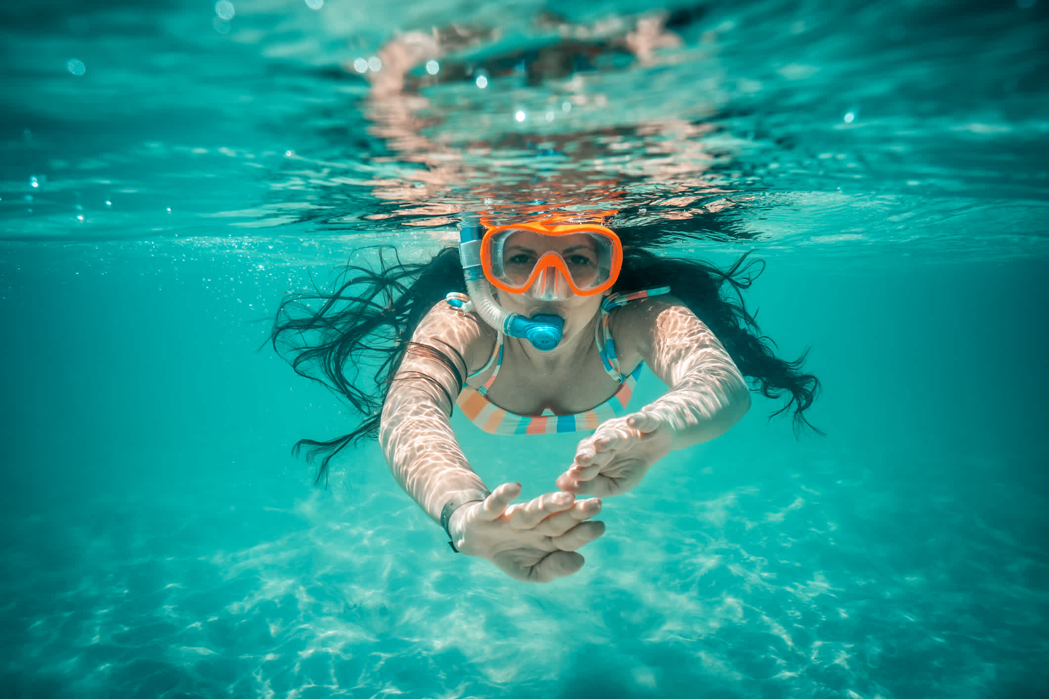 Unterwasseransicht der schönen Frau schwimmen in blauem Meerwasser

