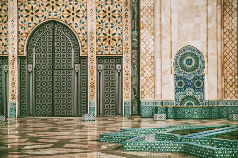 Prächtige marokkanische Moschee mit grünen Türen, bunten Mosaikfliesen und traditionellen geometrischen Mustern.
