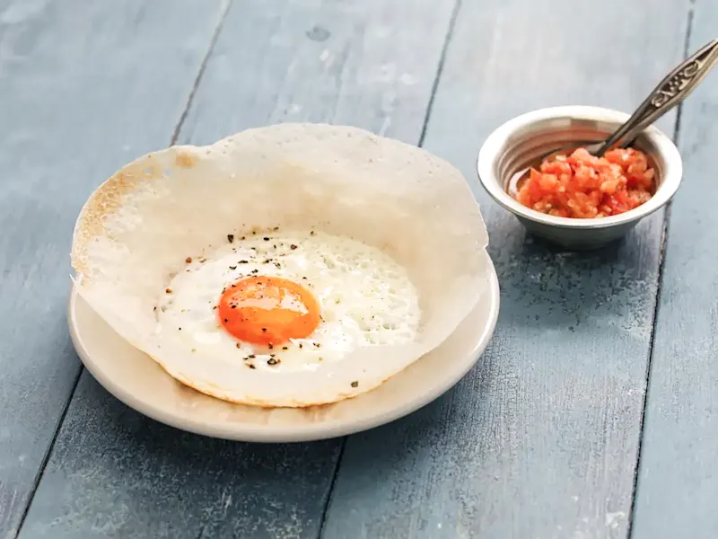 Sri-lankisches Gericht, Hoppers Hoppers, traditionelle sri-lankische Pfannkuchen aus Reismehl mit Ei, serviert mit scharfem Sambol.