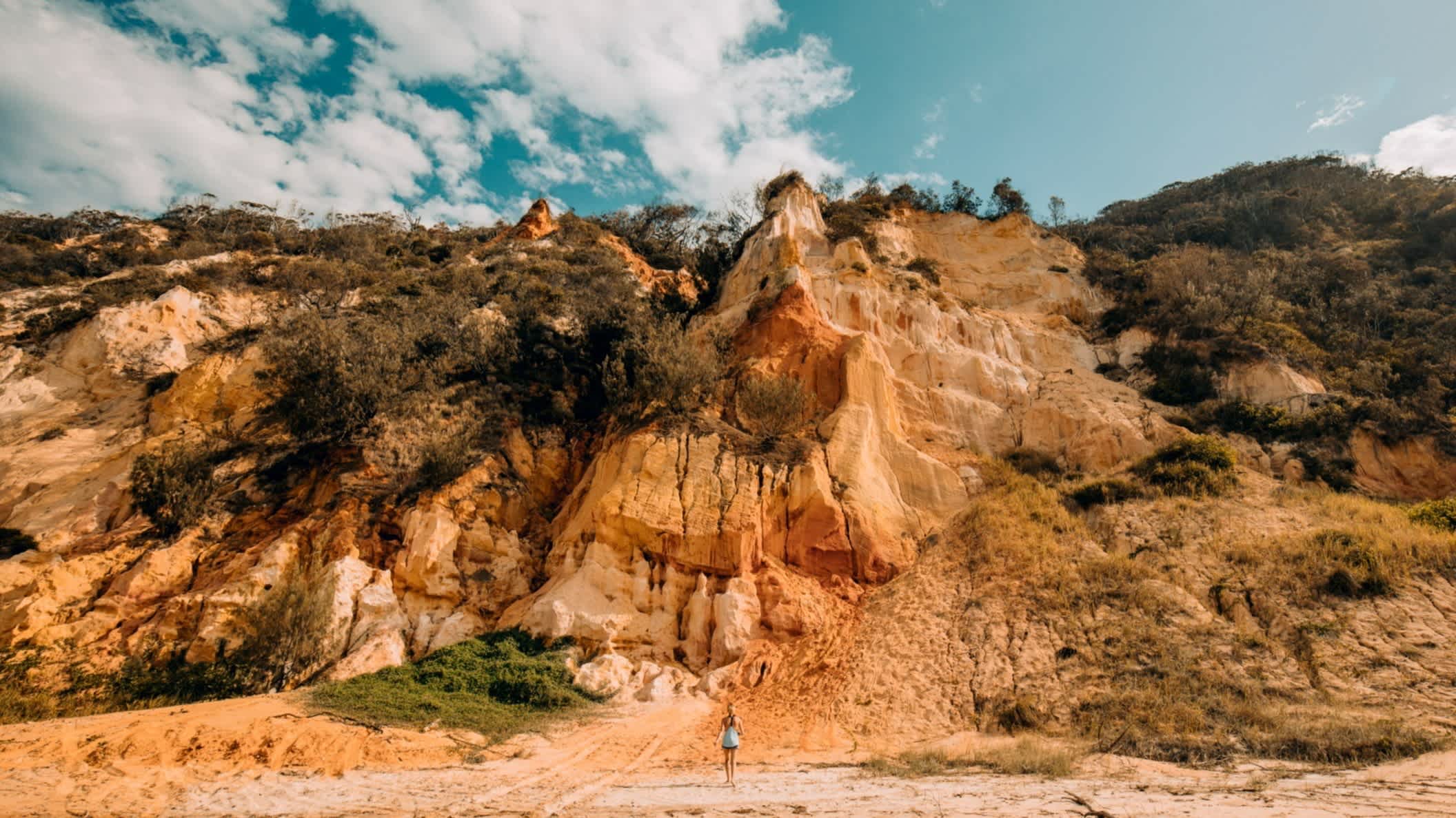 Eine Frau steht am Klippenrand am Rainbow Beach in Queensland, Australien.