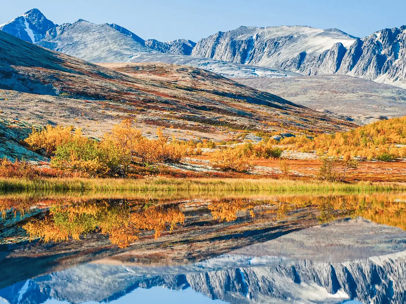Norwegen, Innlandet, Rondane-Nationalpark Herbstliche Landschaft mit Bergen und reflektierendem See. Rondane-Nationalpark, Innlandet, Norwegen.