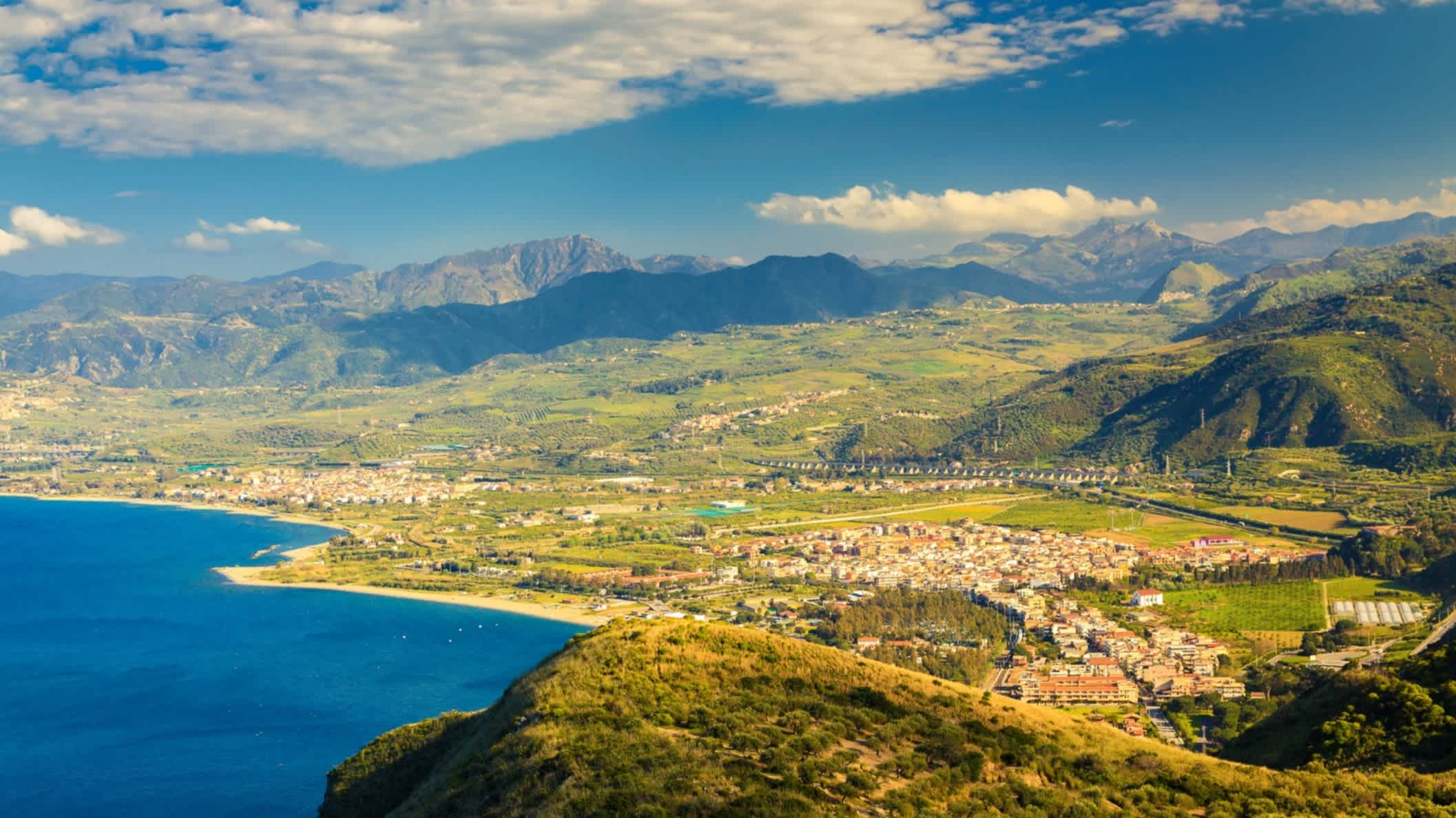 Blick aus der Luft auf eine Stadt und einen Strand in Oliveri  Sizilien, Italien mit Gebirge im Hintergrund.


