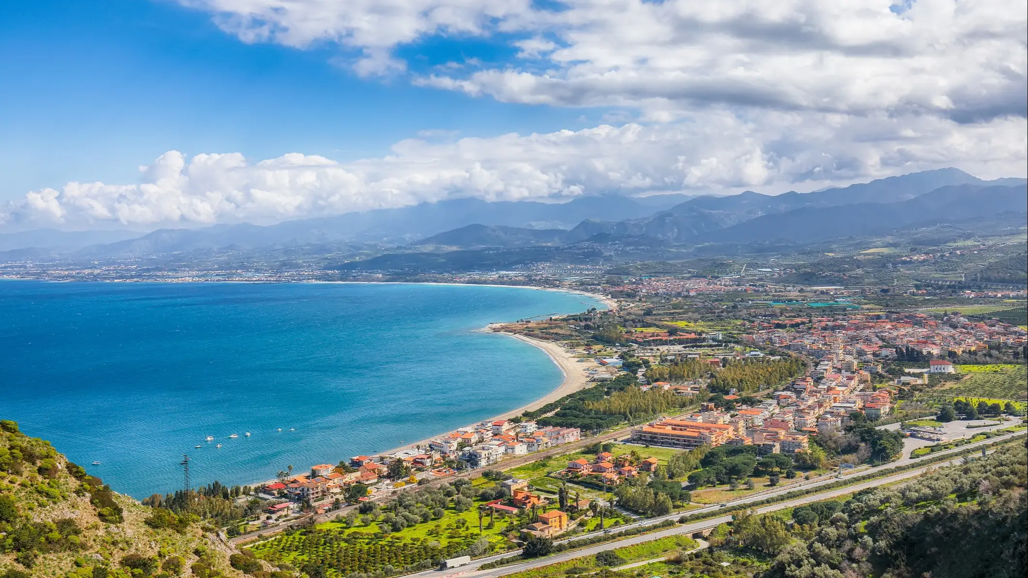 Italien, Sizilien, Oliveri Blick aus der Luft auf eine Stadt und einen Strand in Oliveri Sizilien, Italien mit Gebirge im Hintergrund.