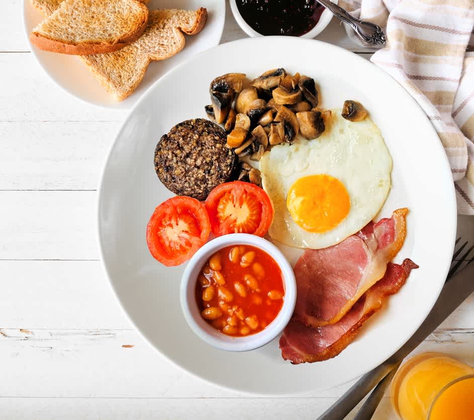 Komplettes schottisches Frühstück mit Haggis, Tischszene über weißem Holz mit Kopierraum