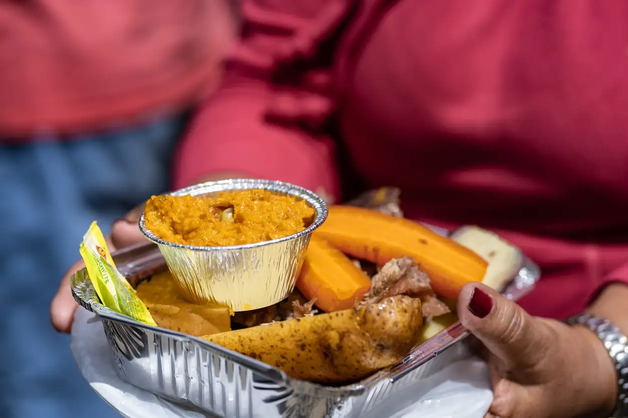 Chili, Curanto Une femme tient un petit plateau de légumes et de viande préparés sous terre dans le cadre de la cérémonie du curanto.