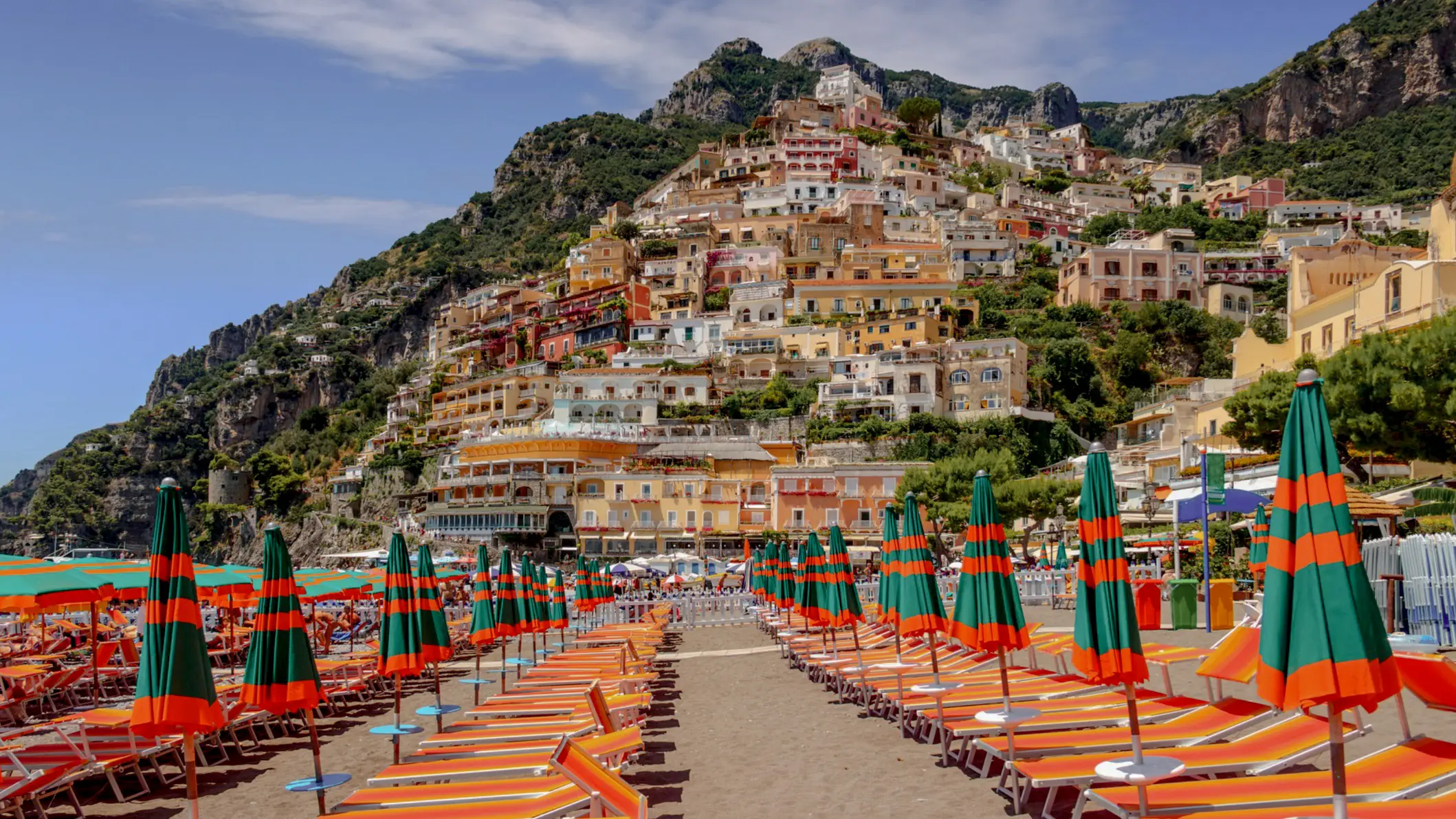 View of the Spiaggia Grande beach and the colorful parasols and sun loungers with the mountain in the background