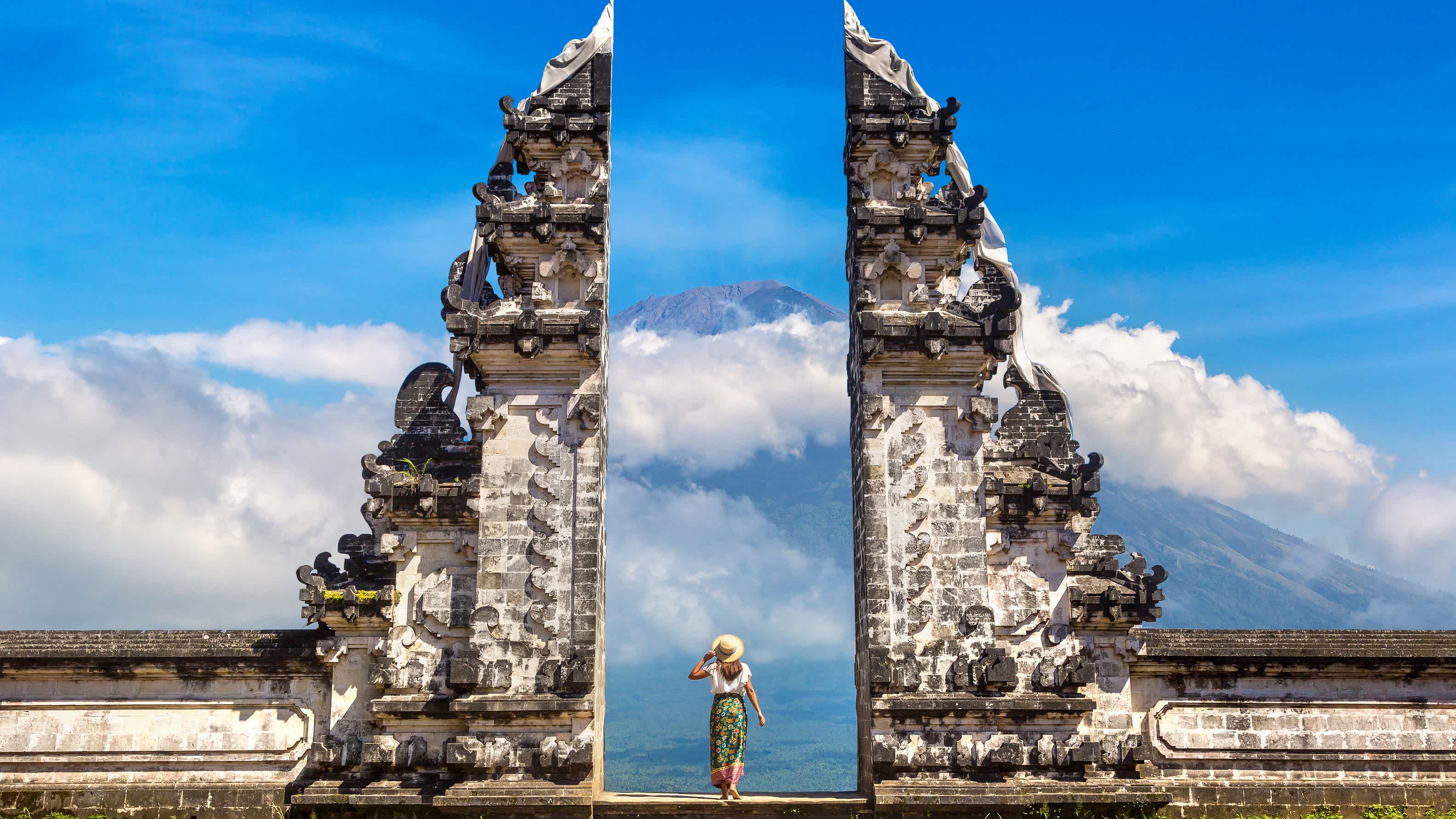 Femme tenant un chapeau au Temple Pura Agung Lempuyang, à Bali, en Indonésie