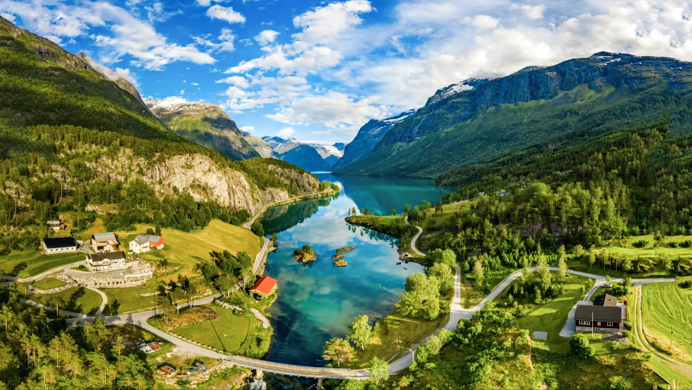 Lac entouré de montagnes et de fermes. Lovatnet, Vestland, Norvège.