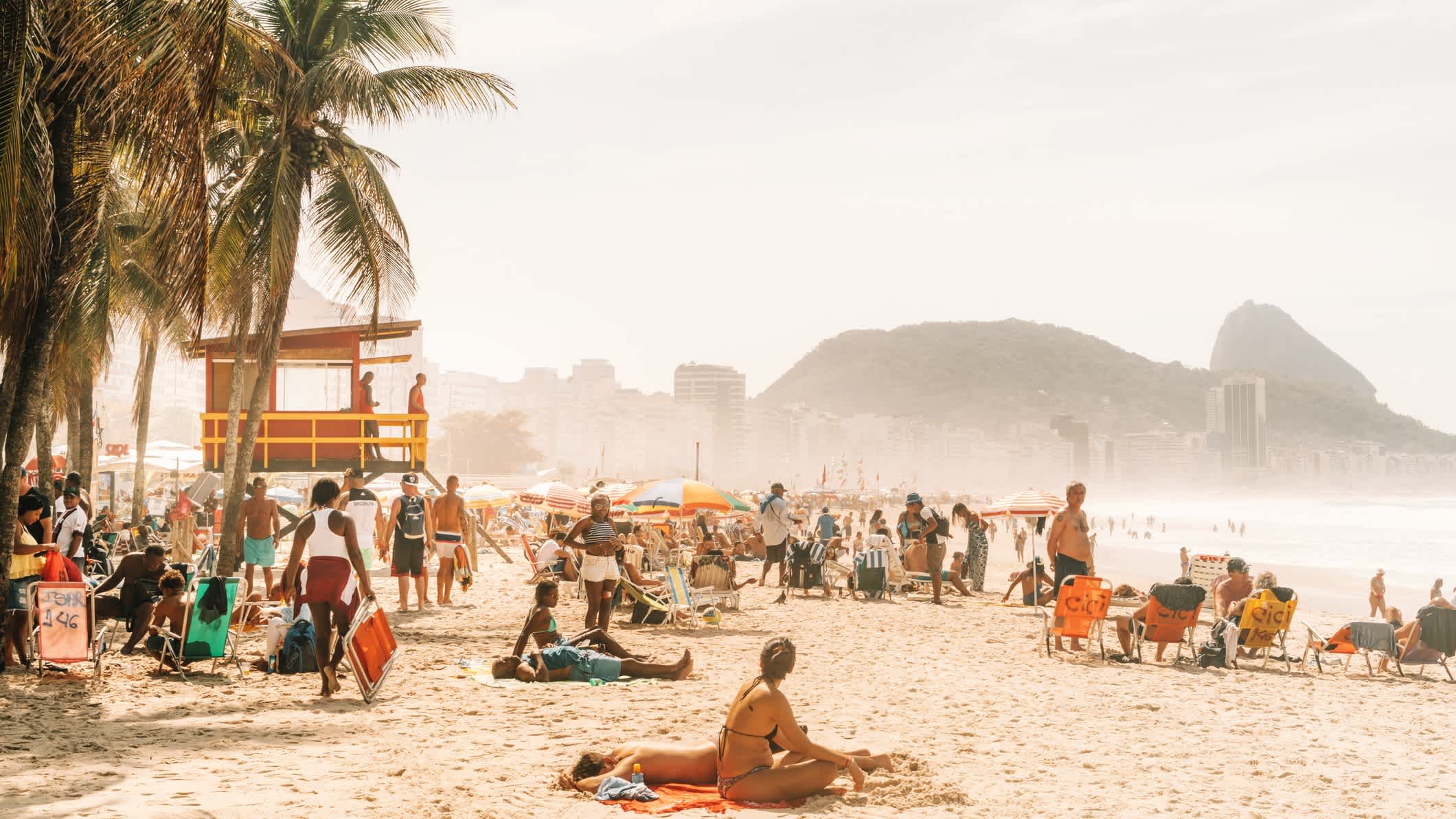 Menschen beim Entspannen und Sonnenbaden am berühmten Copacabana-Strand, Rio de Janeiro, Brasilien